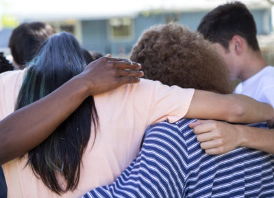 A group of teens with their arms around one another.